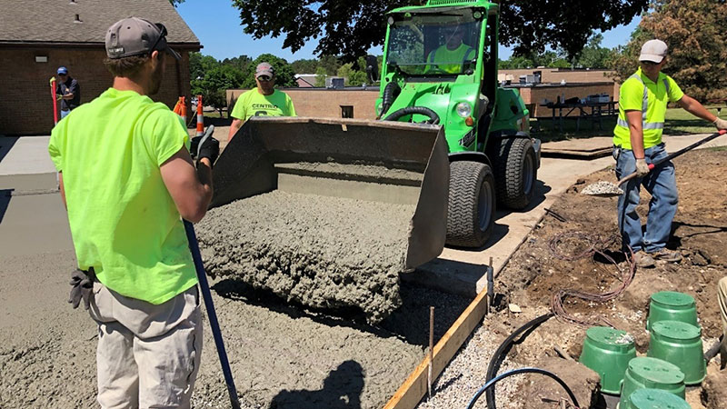 Concrete truck with employees in work gear shoveling pea gravel.