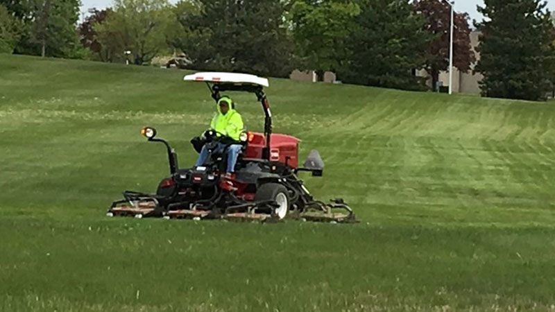 Large riding mower with an Oakland County employee working mowing the grounds lawn.