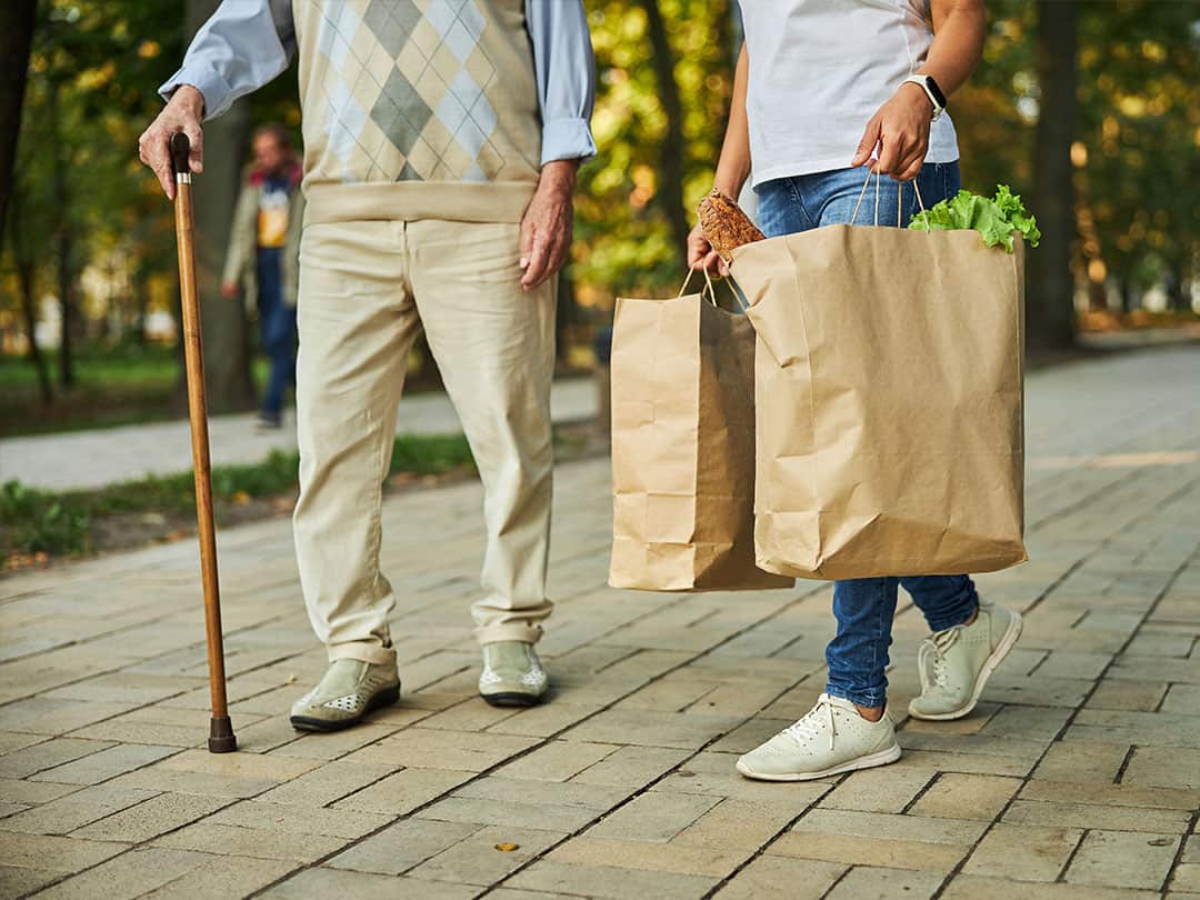 Female holding paper shopping bags in hand near the elderly man.