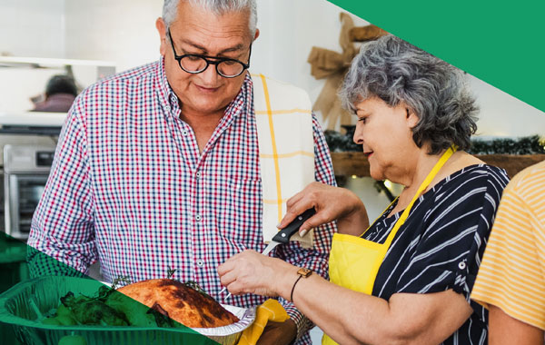 An elderly man and woman cooking in the kitchen.