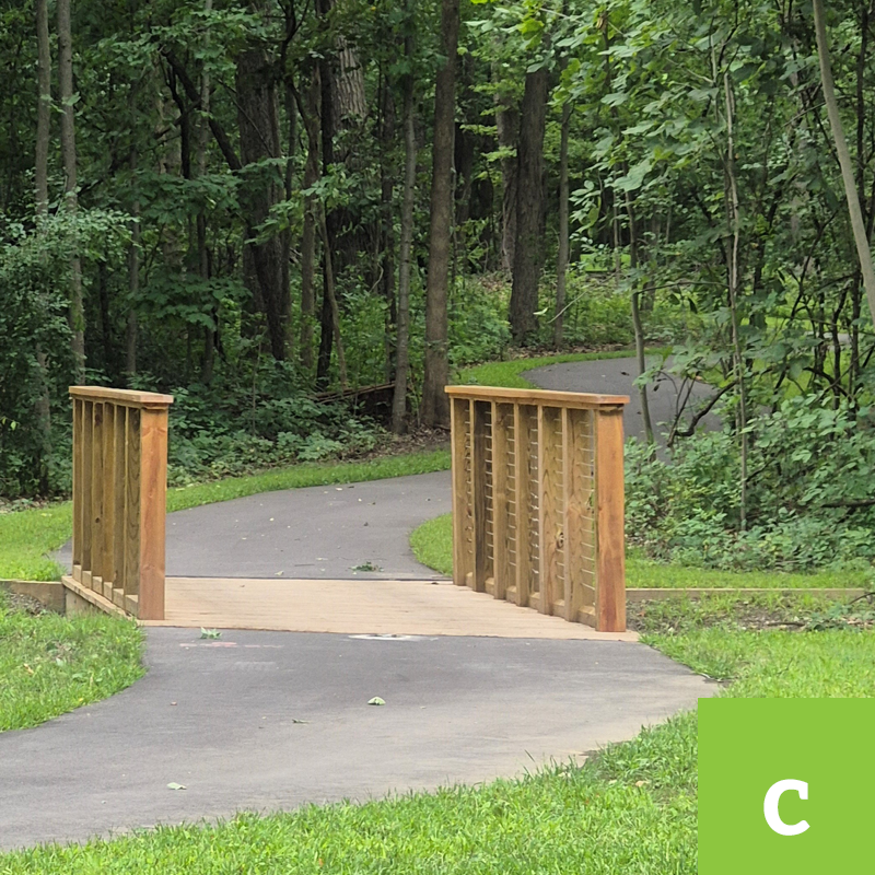 small wooden dock over cement path in wooded area