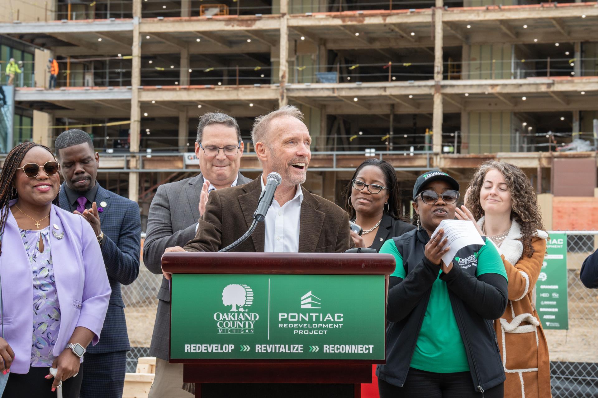 County Executive Dave Coulter speaks at Pontiac redevelopment press conference at the Judson Building with local officials behind him.