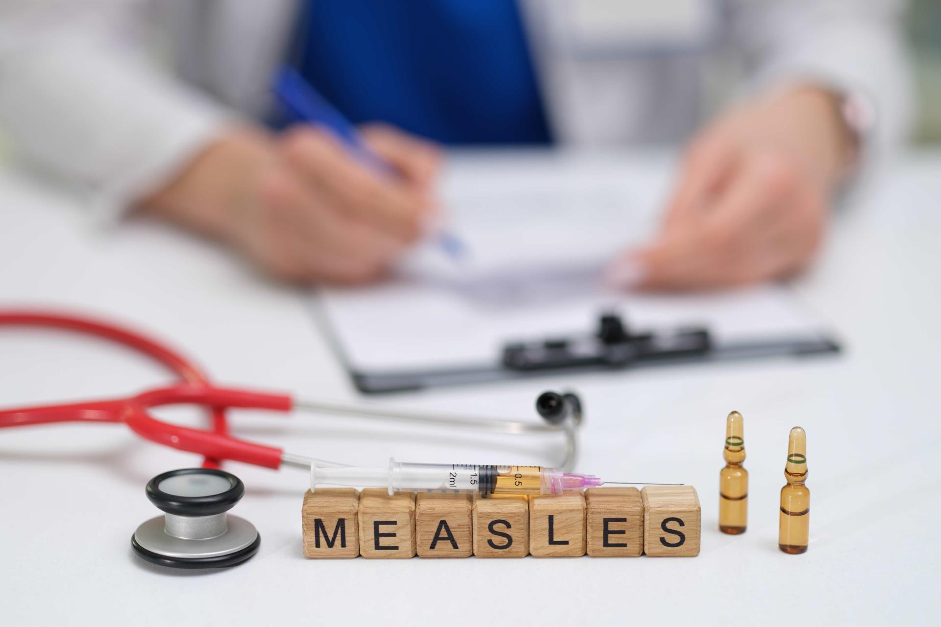 A doctor carefully documents the measles vaccination process, noting the syringes and vials used throughout