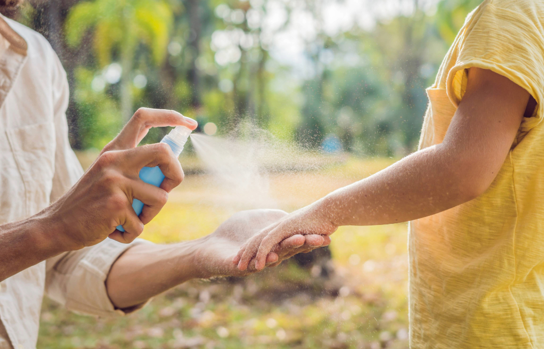 Parent spraying mosquito repellant on child