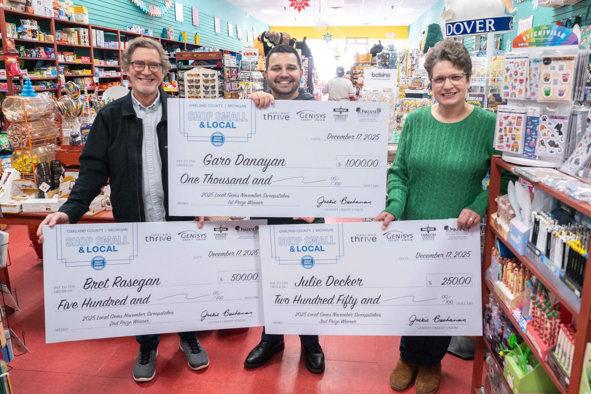 Three people standing with giant checks