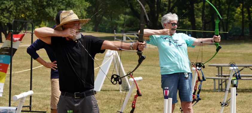 Active adults practicing their archery skills at the park.