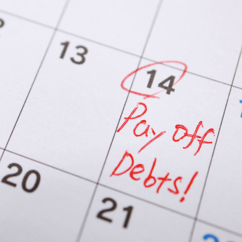 A calendar page shows the number 14 circled in red and Pay off Debts! written next to it in red ink, suggesting a financial reminder or deadline.