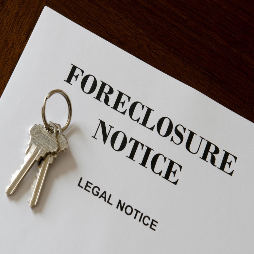 A set of keys lies on a foreclosure notice labeled Legal Notice on a wooden table, conveying a serious and urgent tone regarding property loss.